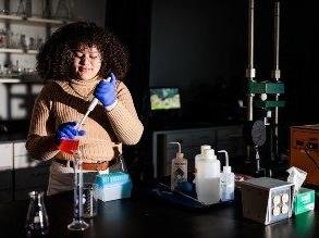 High school student Mattie Smith in a chemistry lab with a bulb syringe and a beaker with other chemistry equipment on the table in front of her